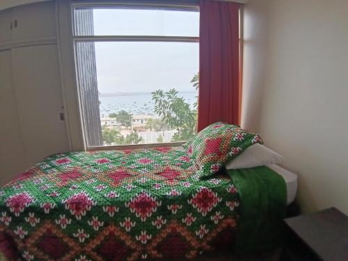 a bedroom with a bed with a flowered blanket and a window at Tongoy Bauhaus - Alojamiento hasta 12 personas in Tongoy