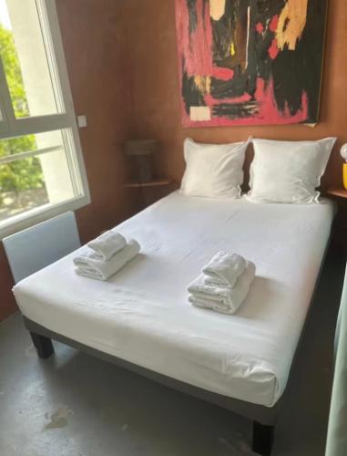 a white bed with two towels on top of it at Petit nid calme à 2 pas de Paris in Ivry-sur-Seine