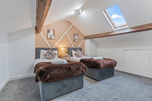 two beds in a room with a skylight at 5BR House Perfect For Contractor Stays By Hyped Properties Short Term Rental Agency Wolverhampton in Wolverhampton