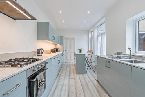 a kitchen with white cabinets and a stove top oven at 5BR House Perfect For Contractor Stays By Hyped Properties Short Term Rental Agency Wolverhampton in Wolverhampton