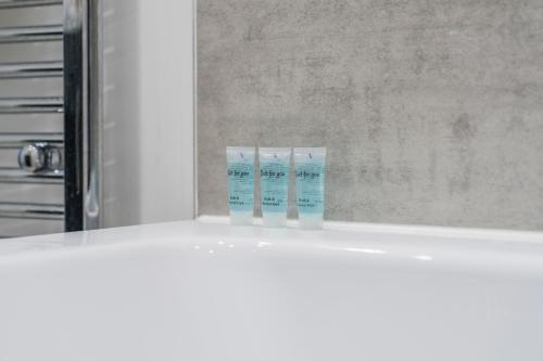 two bottles of toothbrushes on a shelf in a bathroom at 5BR House Perfect For Contractor Stays By Hyped Properties Short Term Rental Agency Wolverhampton in Wolverhampton