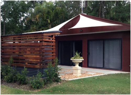 a building with a roof with a planter in front of it at Bielby's Hideaway in Eudlo