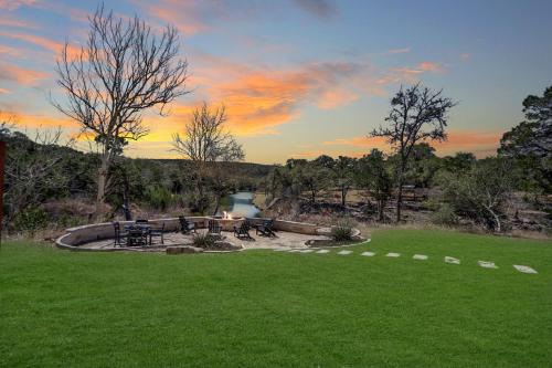 a picnic area with tables and a river at sunset at 2 Creeks in Wimberley