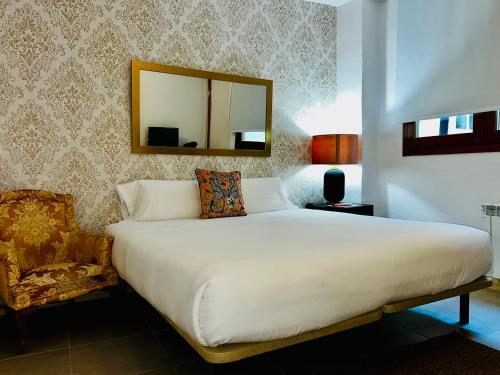 a bedroom with a bed and a mirror and a chair at Santa Rita Rita B&Boutique in Talavera de la Reina