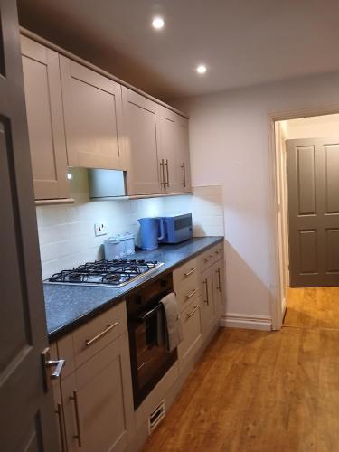 a kitchen with white cabinets and a stove top oven at Modern Coastal Haven Family and Dog friendly in Burry Port