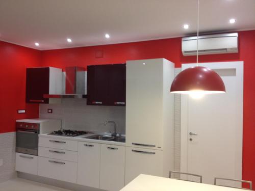 a kitchen with white cabinets and a red wall at Villa Bebe' in Vico Equense