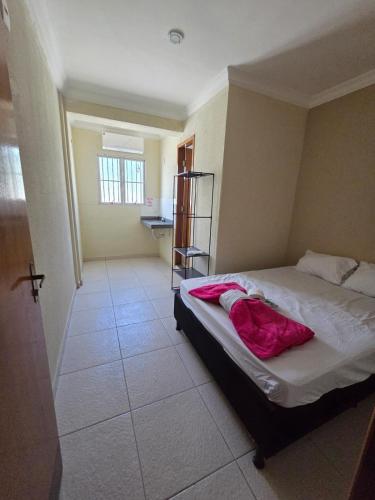 a bedroom with a bed with a pink blanket on it at Hostel Araguaia in Goiânia
