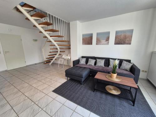 a living room with a couch and a staircase at Ferienhaus Wattgeflüster Neßmersiel in Neßmersiel
