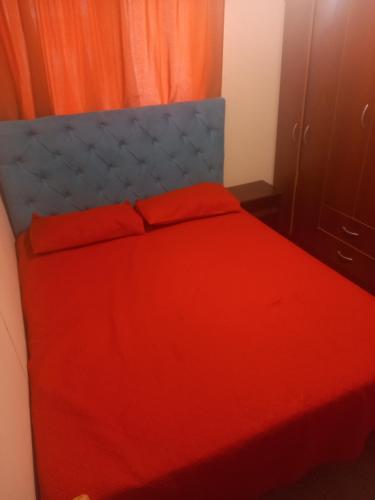 a red bed with orange sheets and pillows on it at acogedora casa nueva in Cerrillo Caiván