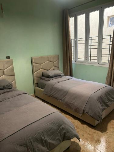 a bedroom with two beds and a window at Maison in Berkane