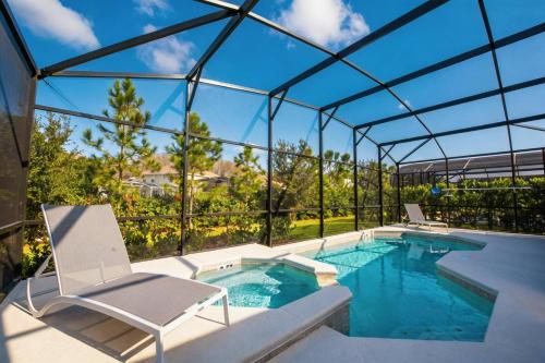 a swimming pool with two chairs and a glass house at Cozy 4BR Villa w Private Pool Spa Near Disney in Kissimmee
