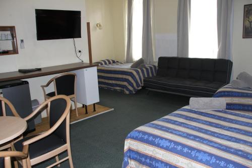 a hotel room with a bed and a couch and a tv at Alpine Heritage Motel in Goulburn