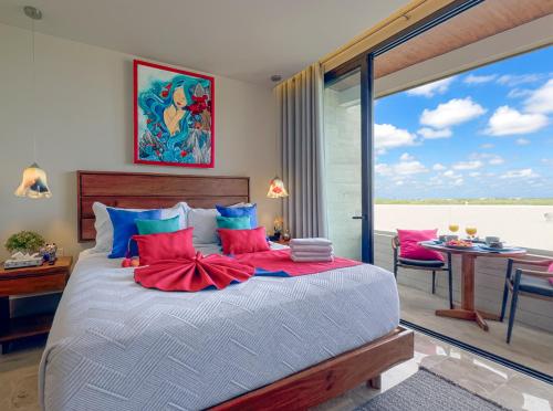 a bedroom with a bed with red and blue pillows at Casa La Aurora - Beachfront Studio and Rooftop Infinity Pool in Puerto Morelos