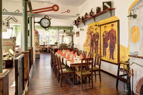 a dining room with tables and chairs and a clock at Ferienhotel Alter Bahnhof garni in Prerow