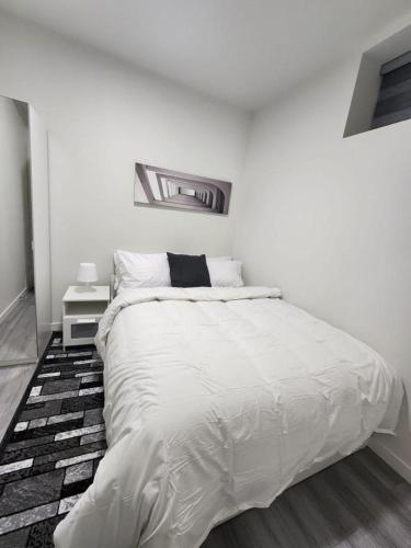 a white bedroom with a large white bed in it at Cozy Home basement suite with private separate entrance in Winnipeg