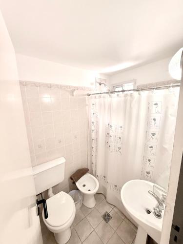 a white bathroom with a toilet and a sink at Hotel Centro SJ in Villa Carlos Paz