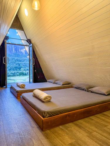 two beds in a room with a large window at A frame Riverston in Matale
