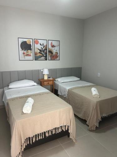 two beds in a room with pictures on the wall at Pousada Aconchego Mineiro in Aracaju
