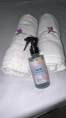 a bottle of perfume on a bed with a pillow at Pousada Aconchego Mineiro in Aracaju
