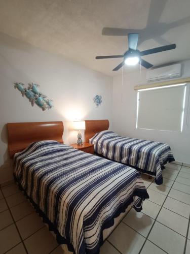 two beds in a room with a ceiling fan at Villa Serena Erizos 2 in San Carlos