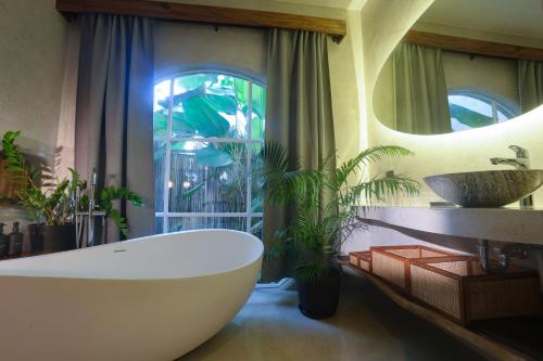 a bathroom with a large white tub and a sink at Lugadia Villas in El Nido
