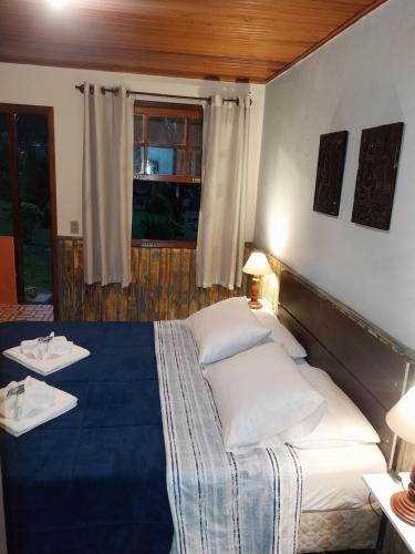 a bedroom with a large bed with white pillows at Chalé Refúgio na Alameda Maringá MG in Bocaina de Minas