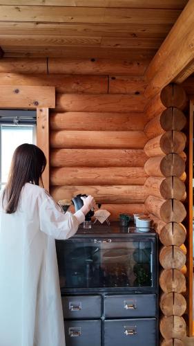 a woman standing in front of a stove in a kitchen at 瀬戸内の離島に泊まる一棟貸しコテージ unodo aoiouchi 焚き火, BBQ, キッチン 最大8名 in Mihara