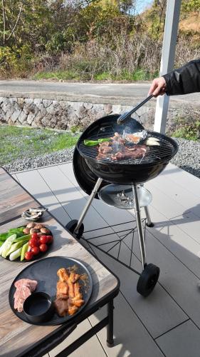 a person cooking food on a grill on a table at 瀬戸内の離島に泊まる一棟貸しコテージ unodo aoiouchi 焚き火, BBQ, キッチン 最大8名 in Mihara