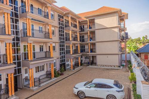 a car parked in a parking lot in front of a building at Alma Hotels Kampala in Kampala