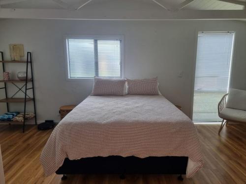 a bed in a bedroom with two windows at Sailrock Studio in Mangawhai