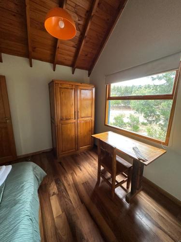 a bedroom with a table and a window and a bed at Aromas de Montaña III in Junín de los Andes