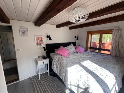 a bedroom with a bed with pink pillows and a chandelier at Hus Skärgården in Figeholm