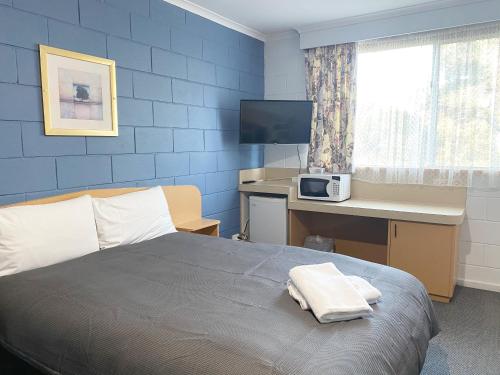 a bedroom with a bed and a desk with a computer at Limestone Coast Tourist Park in Mount Gambier