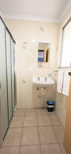 a white bathroom with a sink and a shower at Limestone Coast Tourist Park in Mount Gambier