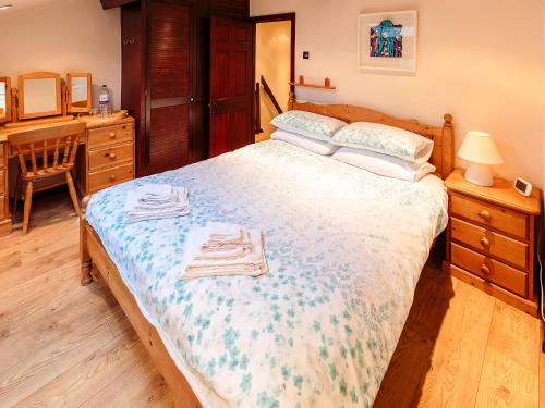 a bedroom with a bed with two towels on it at Millstone Cottage in Bradwell
