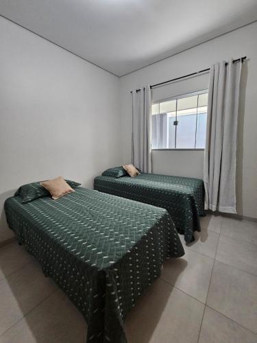 two beds in a room with a window at Apartamento completo - a 3 minutos do centro in Alta Floresta