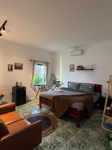 a bedroom with a bed and a couch at Gác Homestay Phan Thiết in Ấp Sung Xuân
