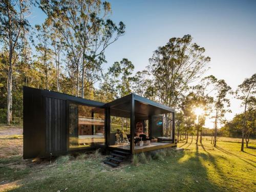 a black house in a field with trees at The Lookout - a Huch experience in Wollombi