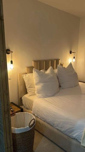 a bedroom with a bed with white pillows and a basket at Instant Charnel Sauna et Jacuzzi Privatif in Istres