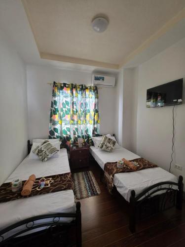 a room with two beds and a window with curtains at Rweydz Guest Inn in Tagbilaran City