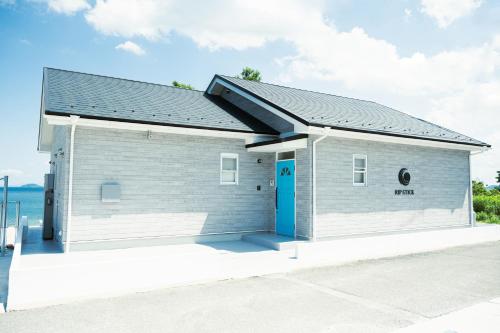 a small gray building with a blue door at RIPSTICK Private Luxury Resort in Otsu