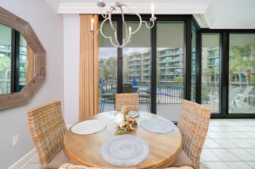 a dining room with a table with chairs and a chandelier at Phoenix on the Bay 1129 condo in Orange Beach