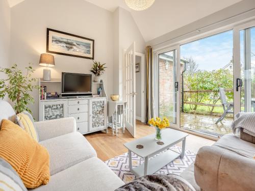 a living room with a couch and a tv at Wisteria Cottage in Heathfield