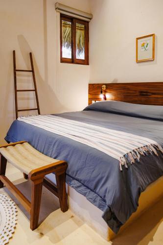 a bedroom with a bed with a wooden headboard and a chair at Villas Indigo Troncones in Troncones
