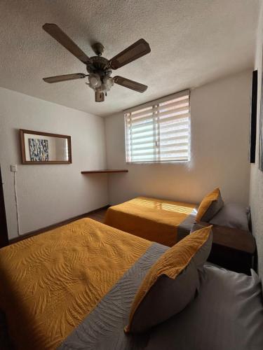 a bedroom with two beds and a ceiling fan at Acogedor y céntrico Departamento in León