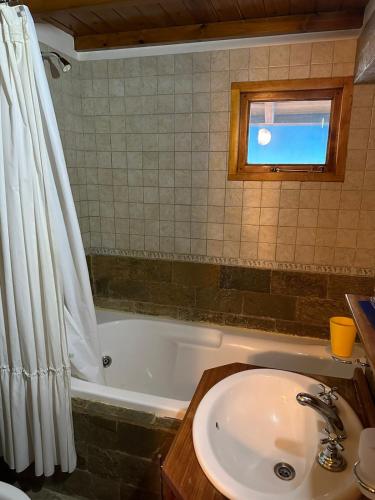 a bathroom with a sink and a bath tub at Aromas de Montaña VIP in Junín de los Andes