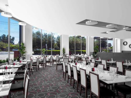 a dining room with tables and chairs and windows at Mantra Melbourne Airport in Melbourne