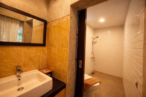 a bathroom with a sink and a toilet and a mirror at Tendan Residence in Legian