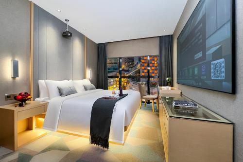 a hotel room with a large bed and a flat screen tv at 啡诺艺术美居 in Guangzhou