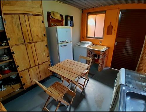 a small kitchen with a table and a refrigerator at Chalé das águas in Cunha
